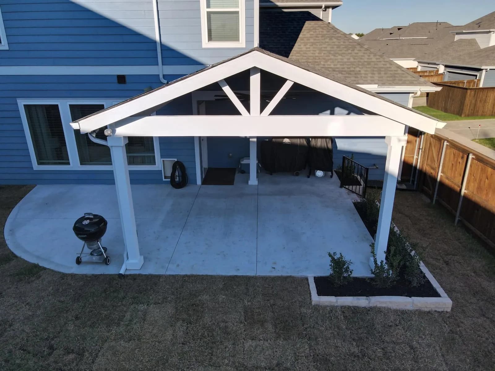 Gabled patio cover with a white truss over a poured patio.