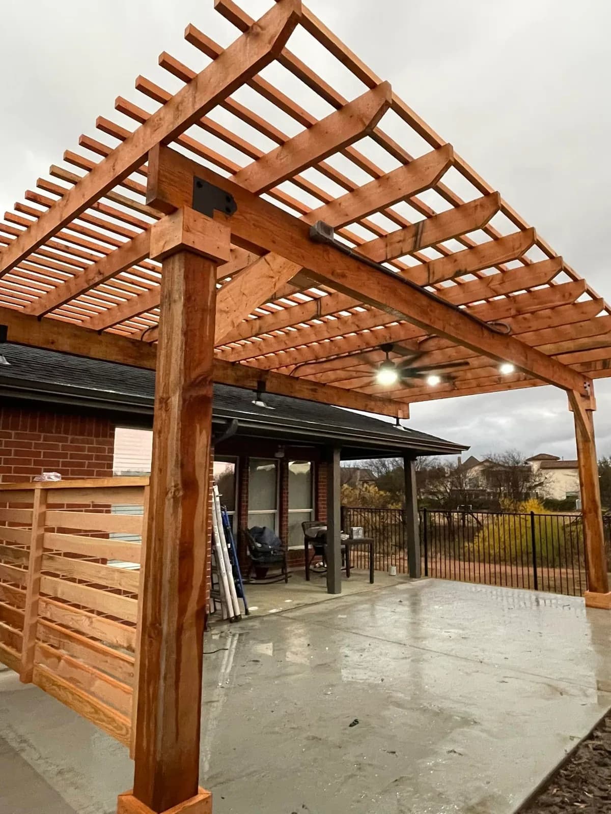 Cedar pergola attached to the house over a concrete patio.